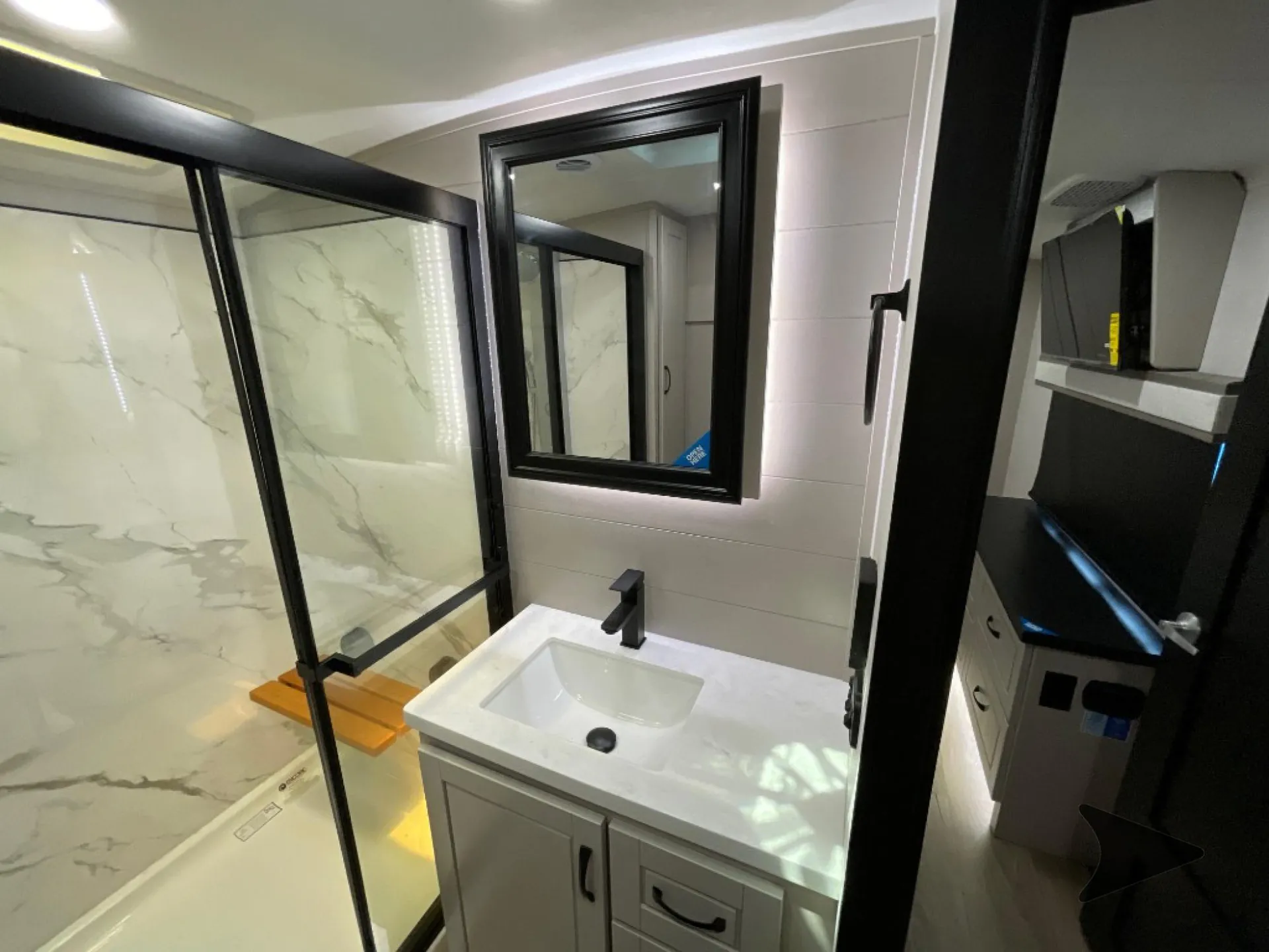 2026 Jayco North Point 377RLBH — Bathroom vanity, mirrored medicine cabinet, and glass-enclosed shower with marble-look wall panels