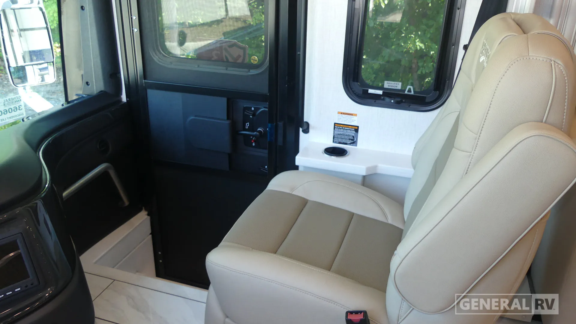 2027 Fleetwood Discovery LXE 40M — Passenger-side cockpit with captain seat, entry door, side windows, grab handle, and dashboard edge