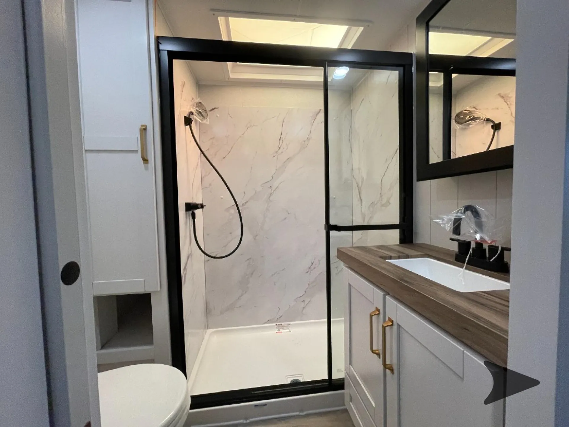 2027 Jayco Eagle 355MBQS — Bathroom with glass-enclosed shower, toilet, vanity sink, mirrored cabinet, and skylight