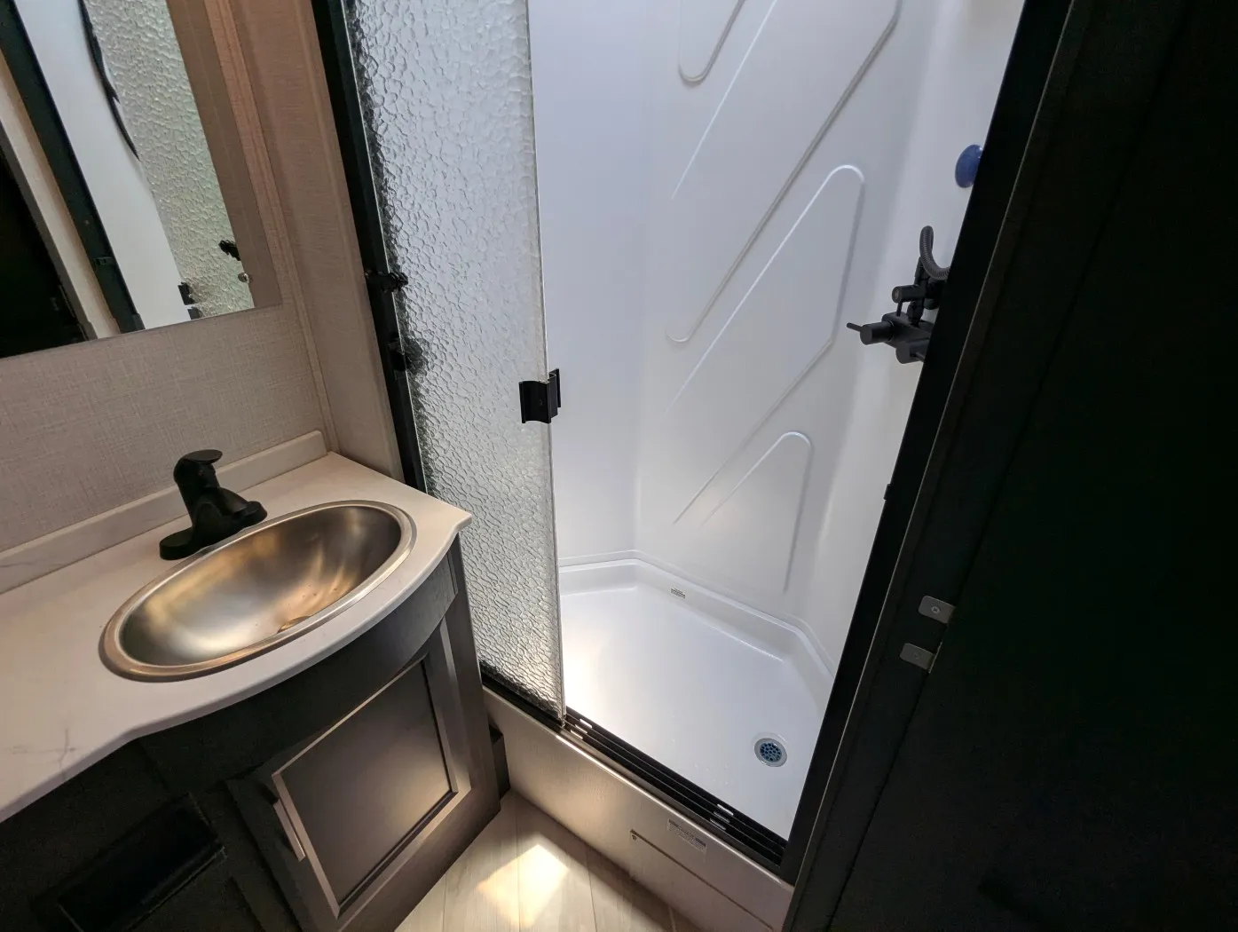 2026 Holiday Rambler Invicta 36Y — Bathroom shower beside a compact vanity with oval sink, faucet, mirror, and cabinet storage