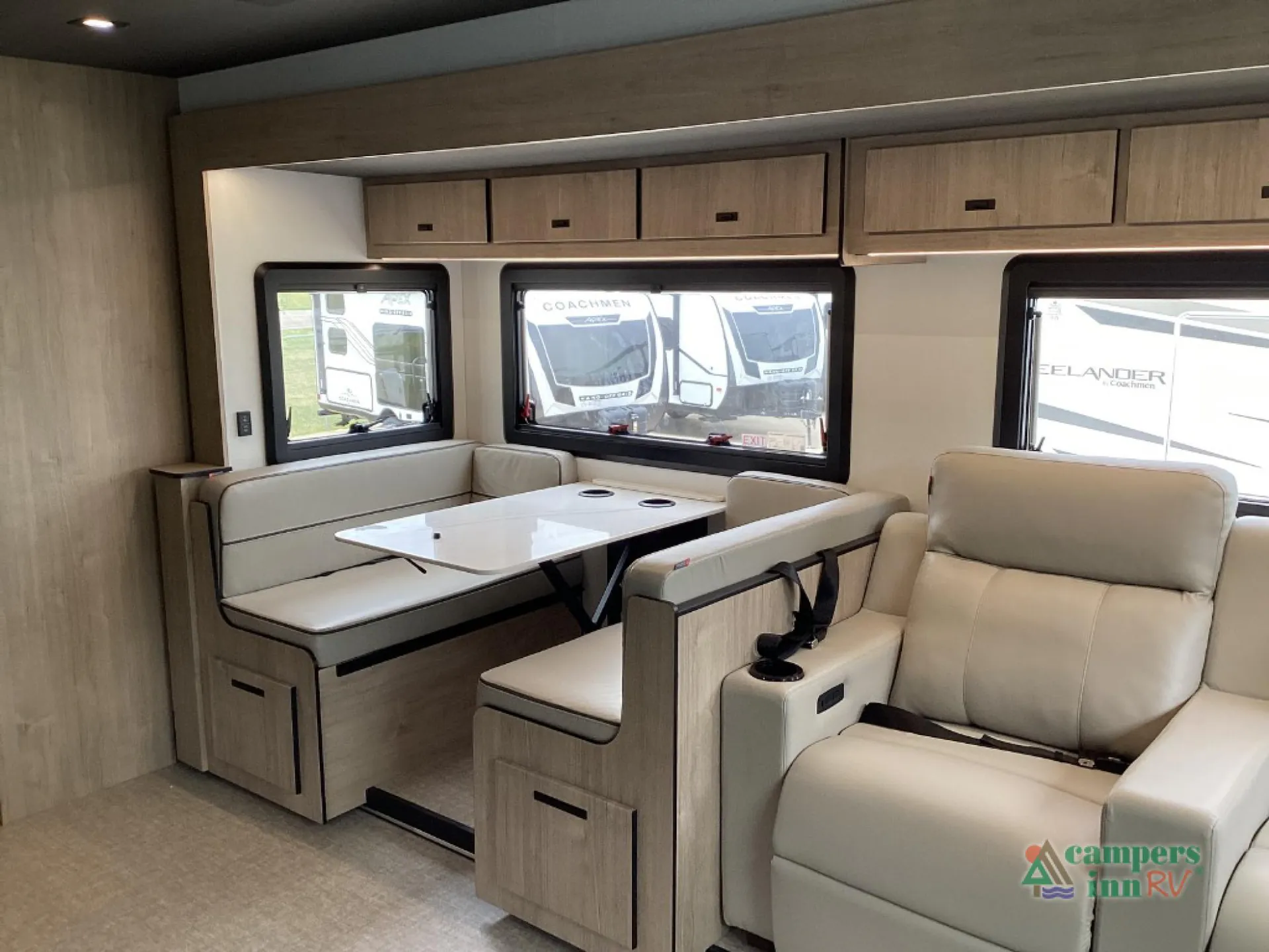 2027 Grand Design Lineage Series F 31ZW — Dinette with table and bench seating beside two reclining lounge seats, overhead cabinets, and windows