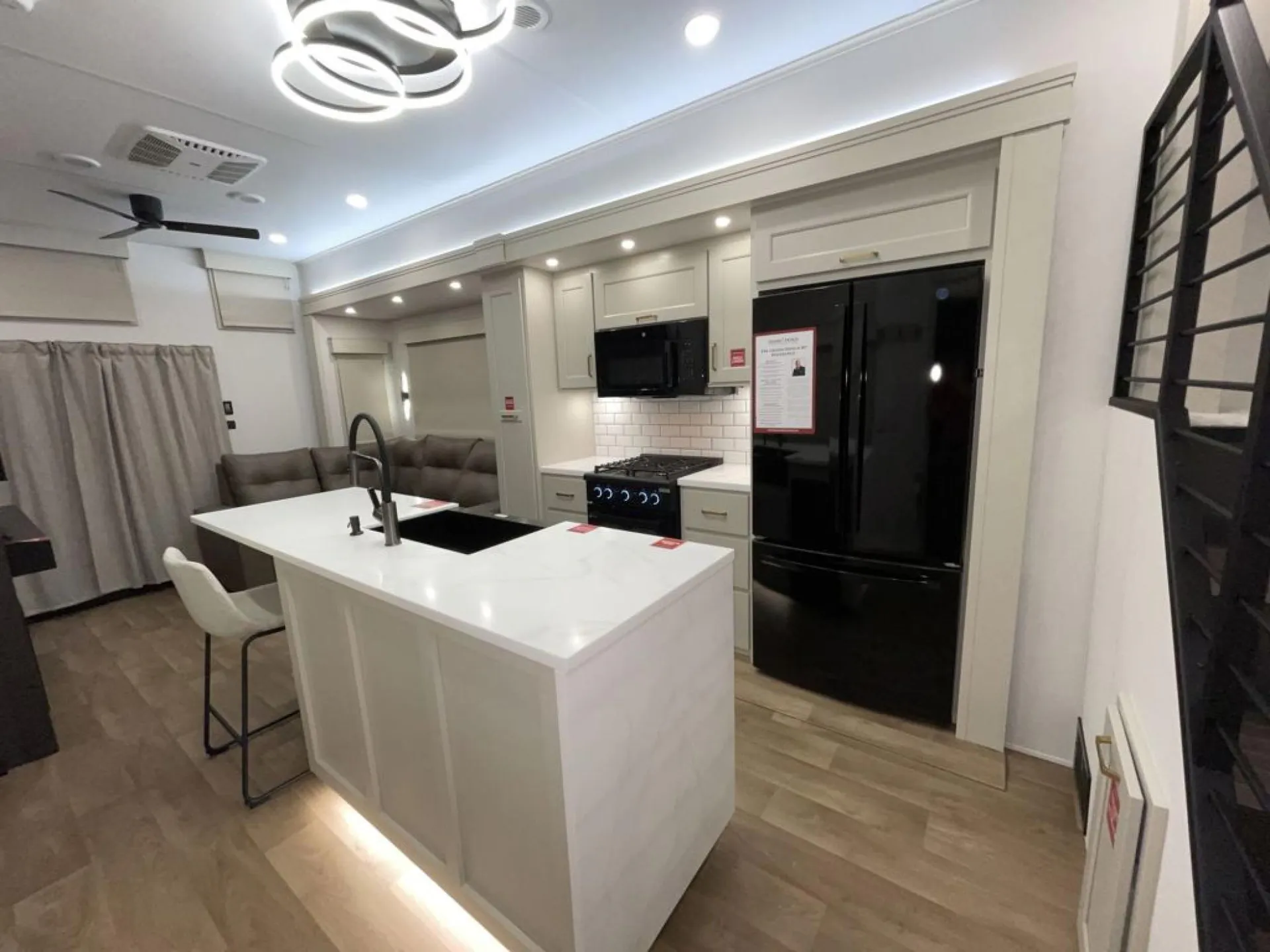 2026 Grand Design Foundation 42GD — Large kitchen island with sink, range, microwave, refrigerator, and a sectional lounge visible beyond
