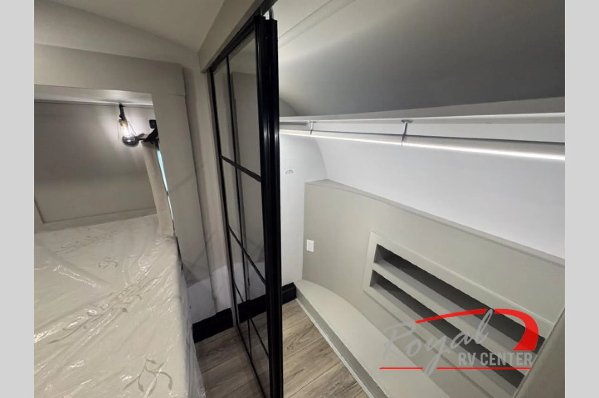2026 Brinkley Model Z 3610 — Bedroom with a plastic-wrapped bed, black-framed enclosure, wall vent, and overhead closet rail