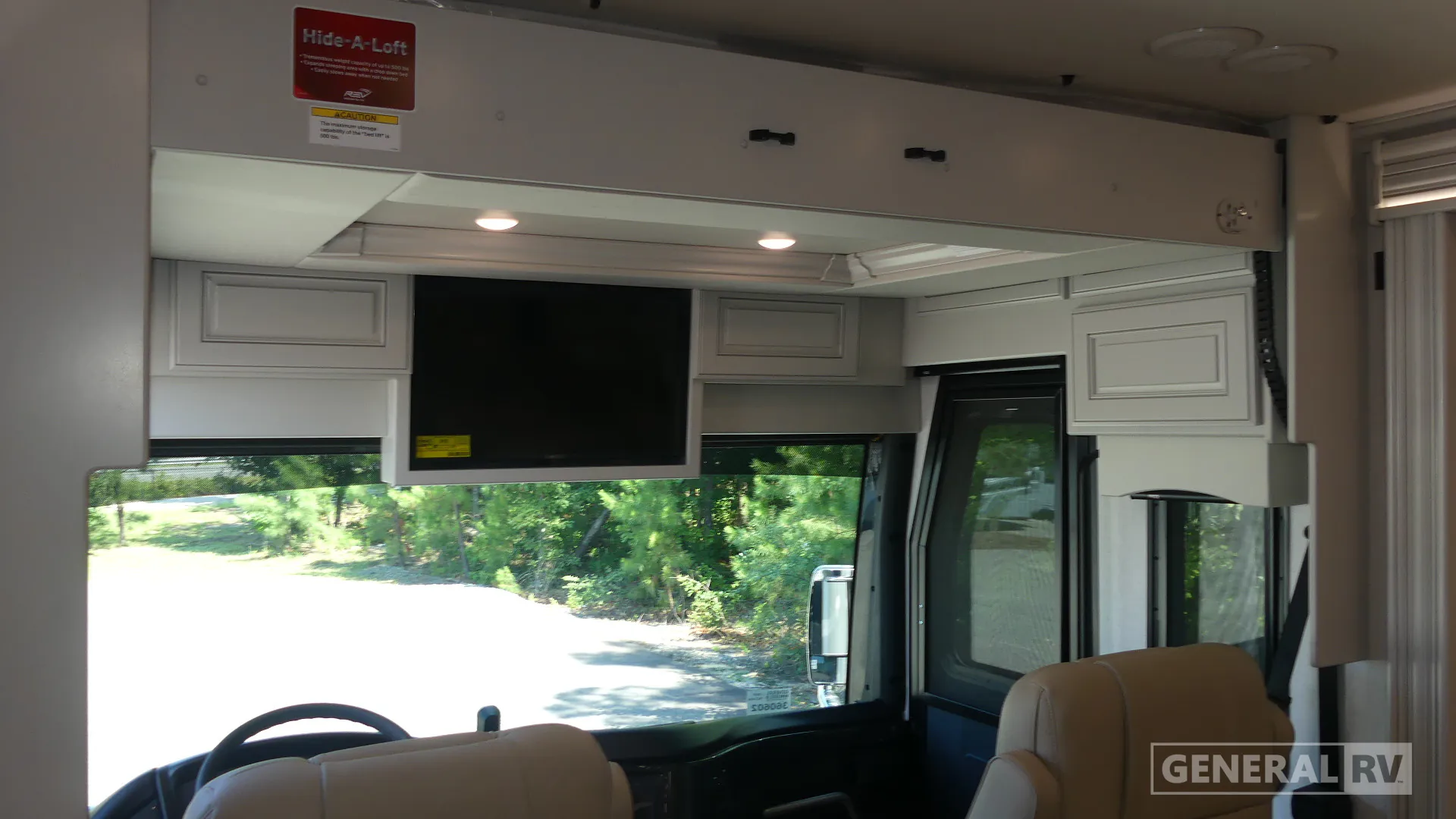 2027 Fleetwood Discovery LXE 40M — Over-cab loft platform above the Class A cockpit, with overhead storage, television, windshield, and captain seats below
