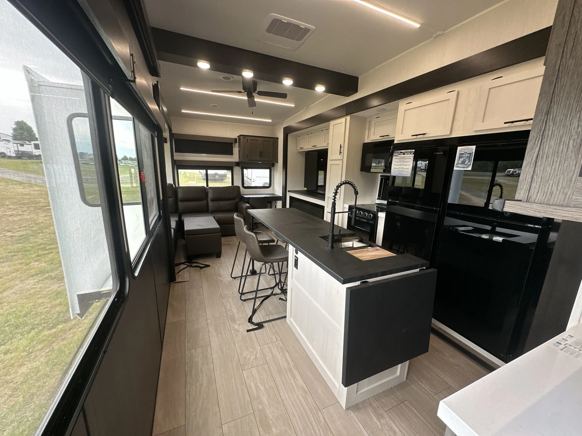 2026 Forest River Arctic Wolf 38LEAH.G — Fifth wheel kitchen island and appliances overlook a dining table and lounge seating with expansive windows
