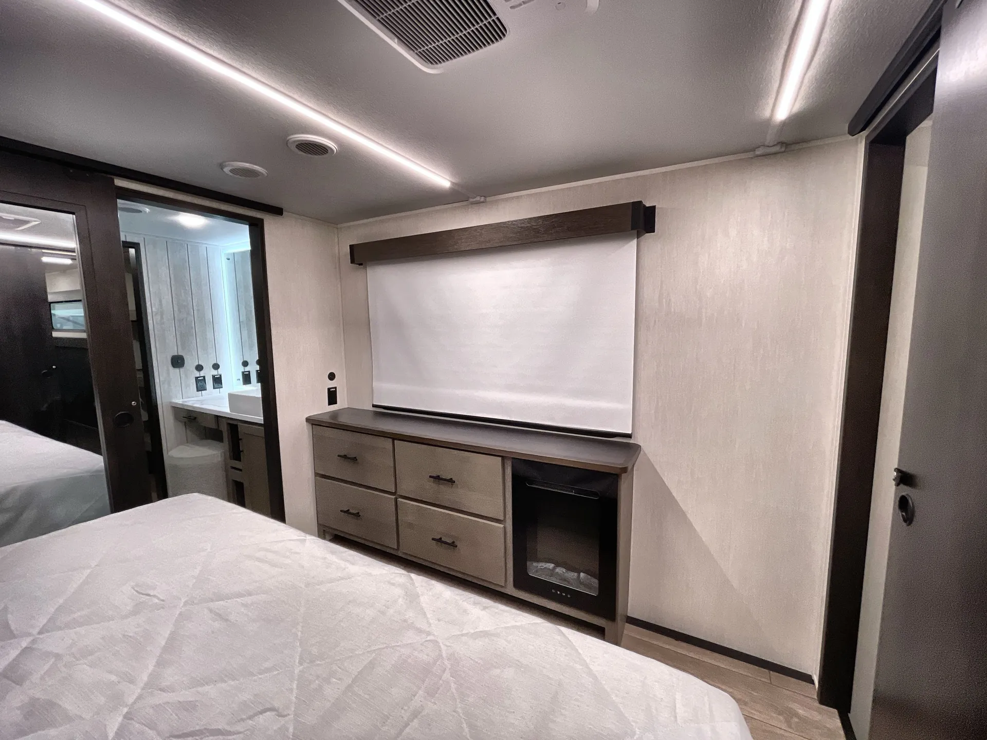 2026 Forest River Arctic Wolf 38LEAH.G — Main bedroom with bed, dresser, television, window shade, and visible bathroom doorway