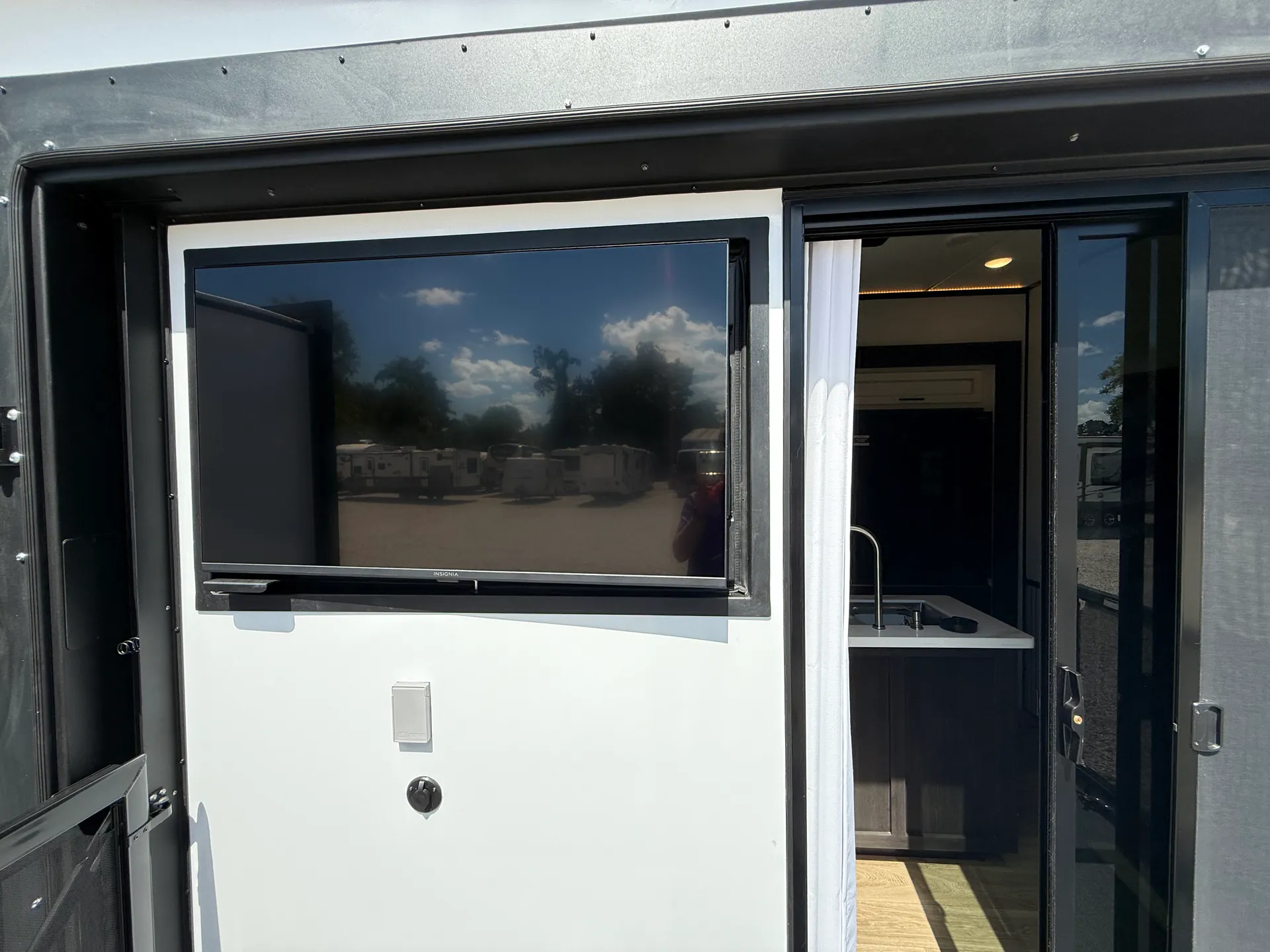2027 Forest River Sabre 38RVHUNTER — Exterior photograph showing the RV wall, mounted television, and open entry doorway