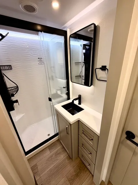 2026 Brinkley Model Z 3610 — Bathroom with glass shower, black fixtures, vanity sink, drawers, and wall mirror
