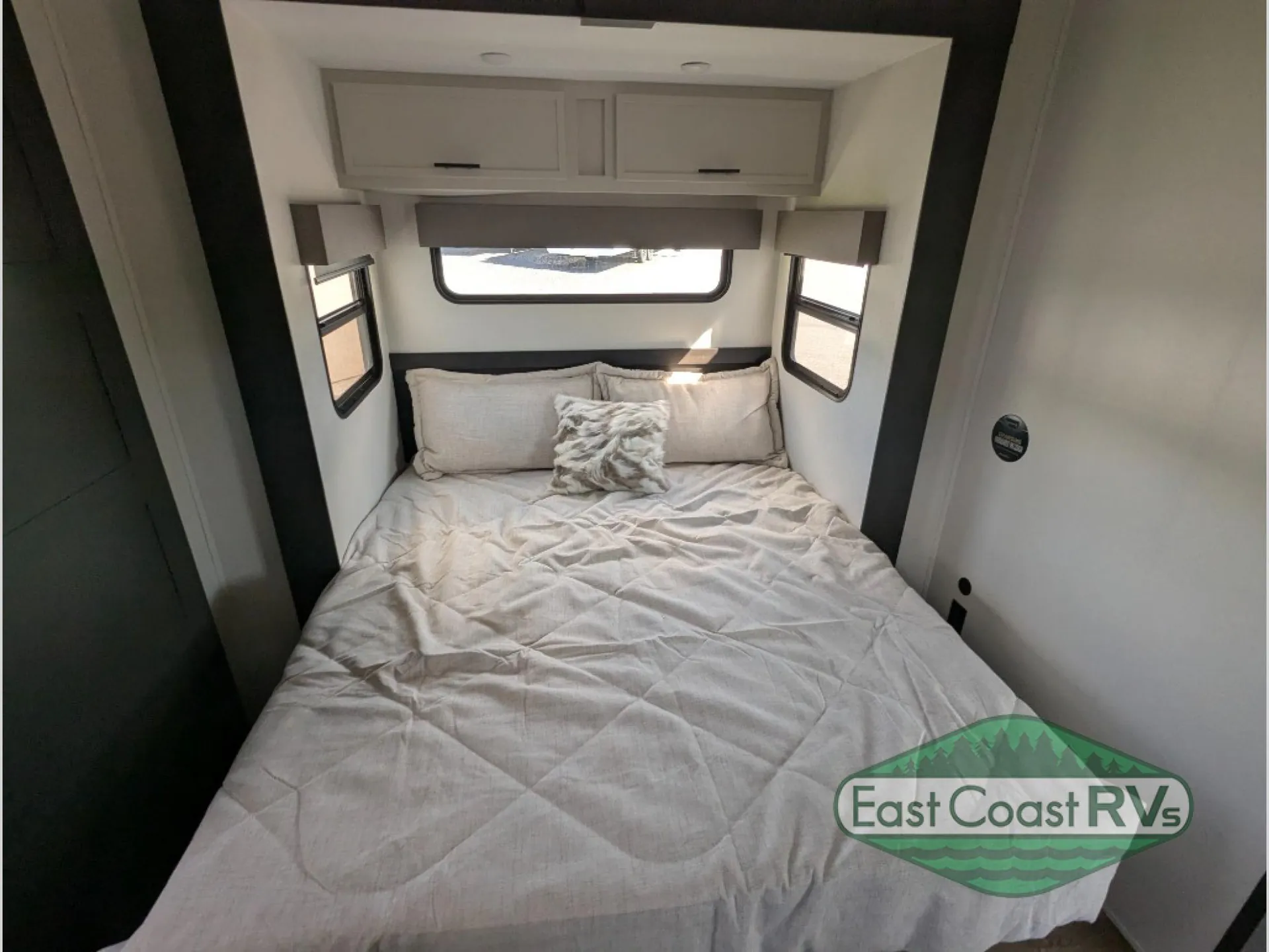 2027 Forest River Sanibel 40BUNK — Enclosed fifth-wheel bedroom with a made bed, side windows, and overhead storage cabinets