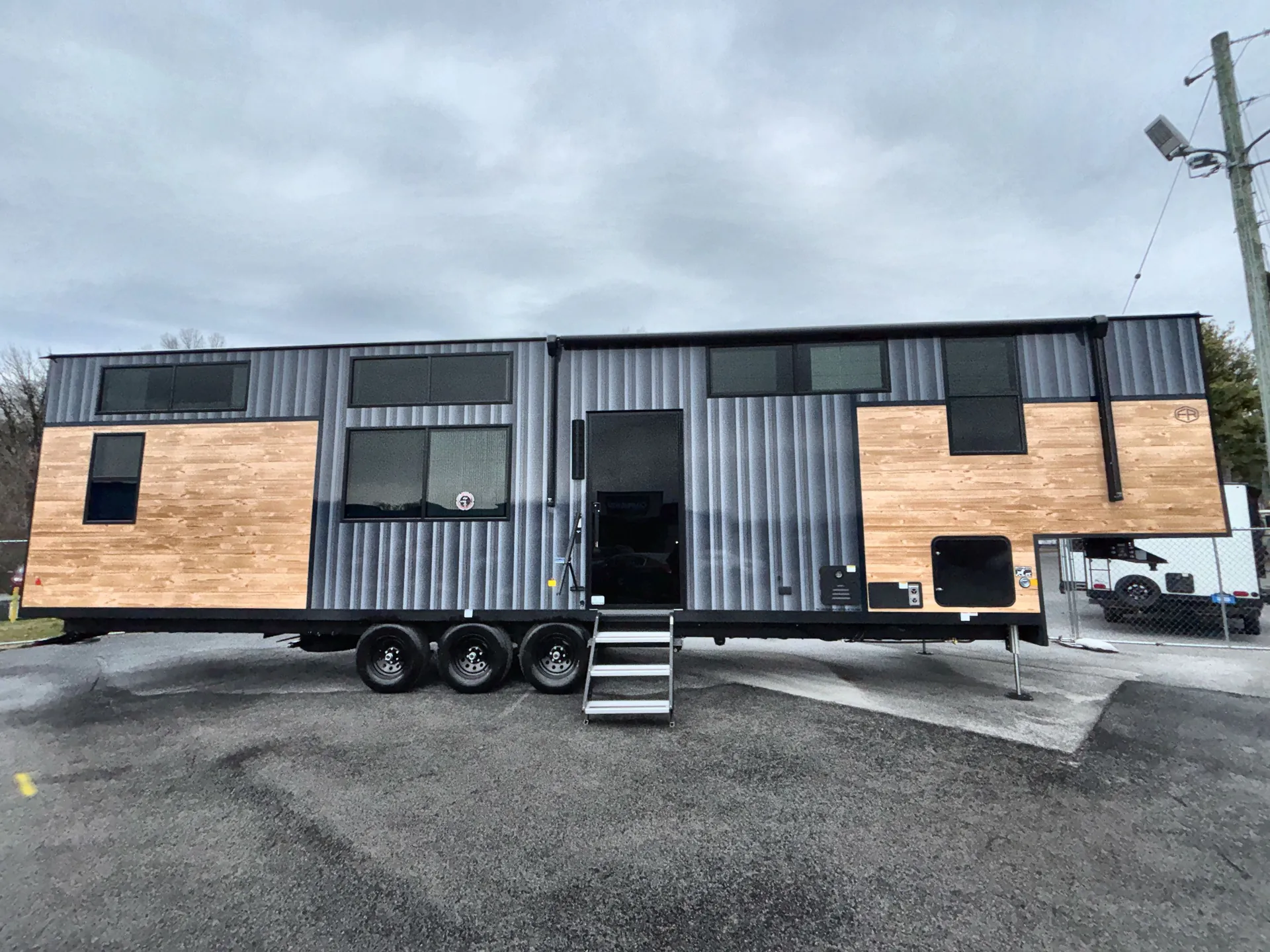 2026 Forest River Cedar Creek Cottage 41FWC — Full side photograph visibly shows the RV shell, triple axle wheels, entry door, windows, siding, and exterior-installed features