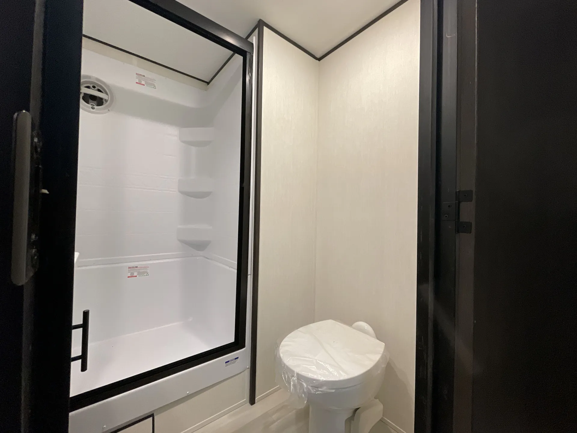 2026 Forest River Cherokee Wolf Pack 397STAY — Bathroom with a glass-enclosed shower, corner shelves, ventilation grille, and toilet