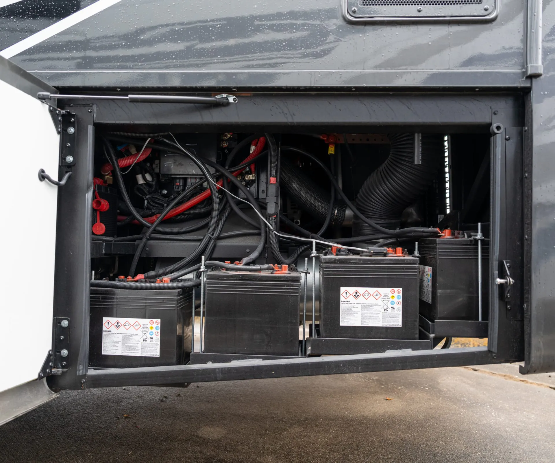 2026 Fleetwood Discovery LXE 40G — Open exterior bay visibly shows multiple batteries, cabling, and electrical/mechanical components