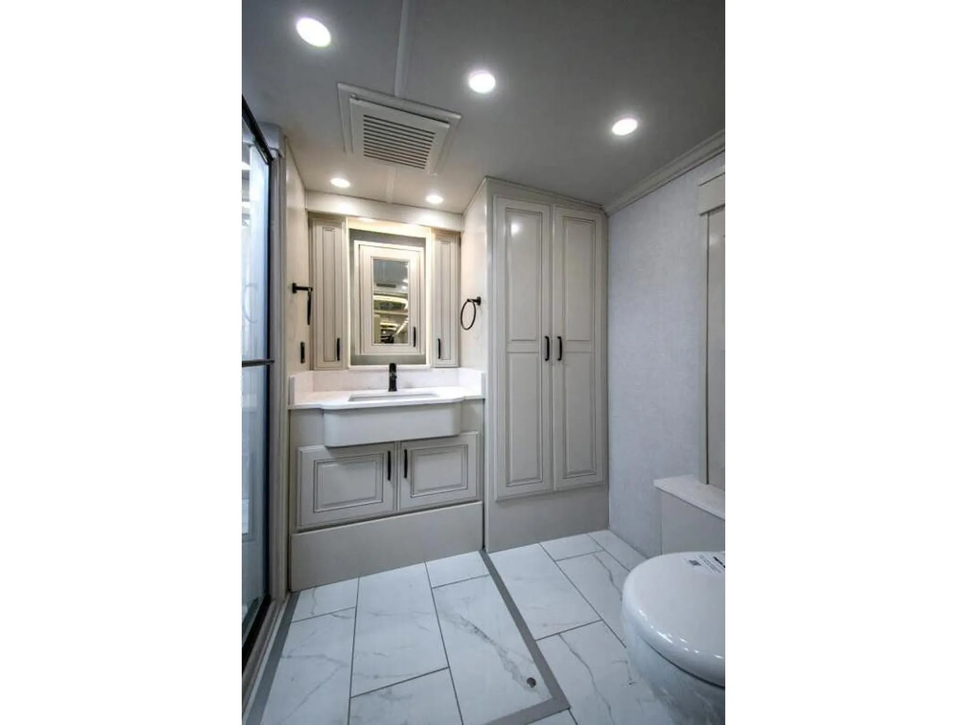 2026 American Coach American Dream 45A — Class A motorhome bathroom with vanity, mirrored medicine cabinet, tall storage cabinet, toilet, and tiled floor