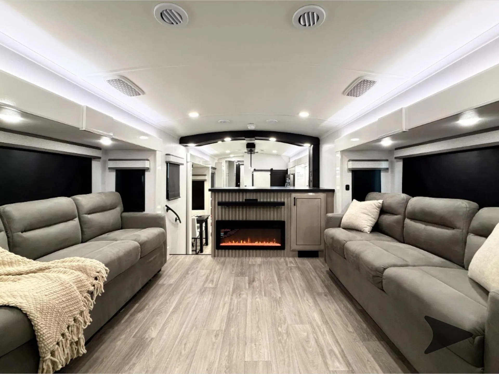 2027 Jayco Pinnacle 39FLOK — Fifth wheel living room with opposing sofas, fireplace, cabinetry, and a kitchen counter beyond