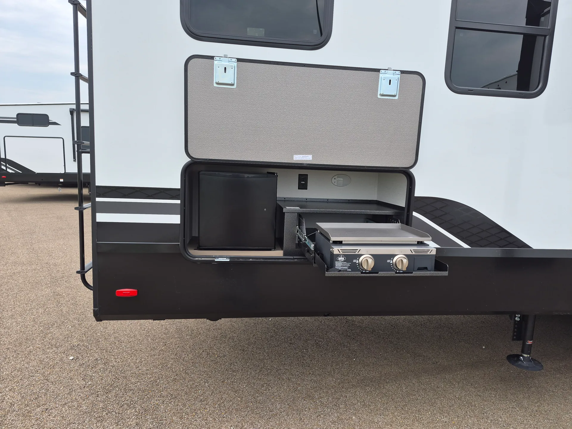 2027 Grand Design Reflection 362TBS — Exterior-installed outdoor kitchen is visibly open, with a slide-out griddle and adjacent exterior compartment