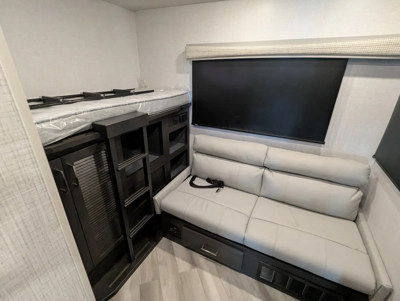2026 Holiday Rambler Invicta 36Y — Living area with a reclining sofa, overhead cabinetry, shelving, window shade, and entertainment storage