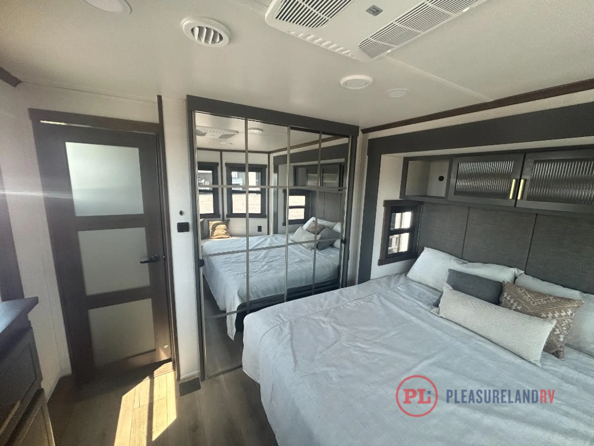 2026 Forest River Cedar Creek Cottage 41FWC — Enclosed bedroom with a made bed, mirrored wardrobe doors, overhead cabinets, and entry door