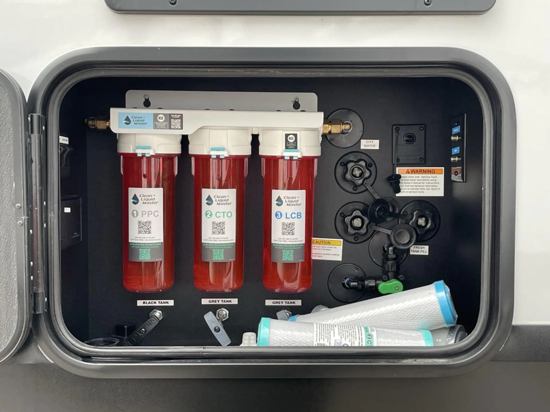 2026 Grand Design Foundation 42GD — Open exterior service compartment visibly contains water filtration, tank outlets, and utility hookups