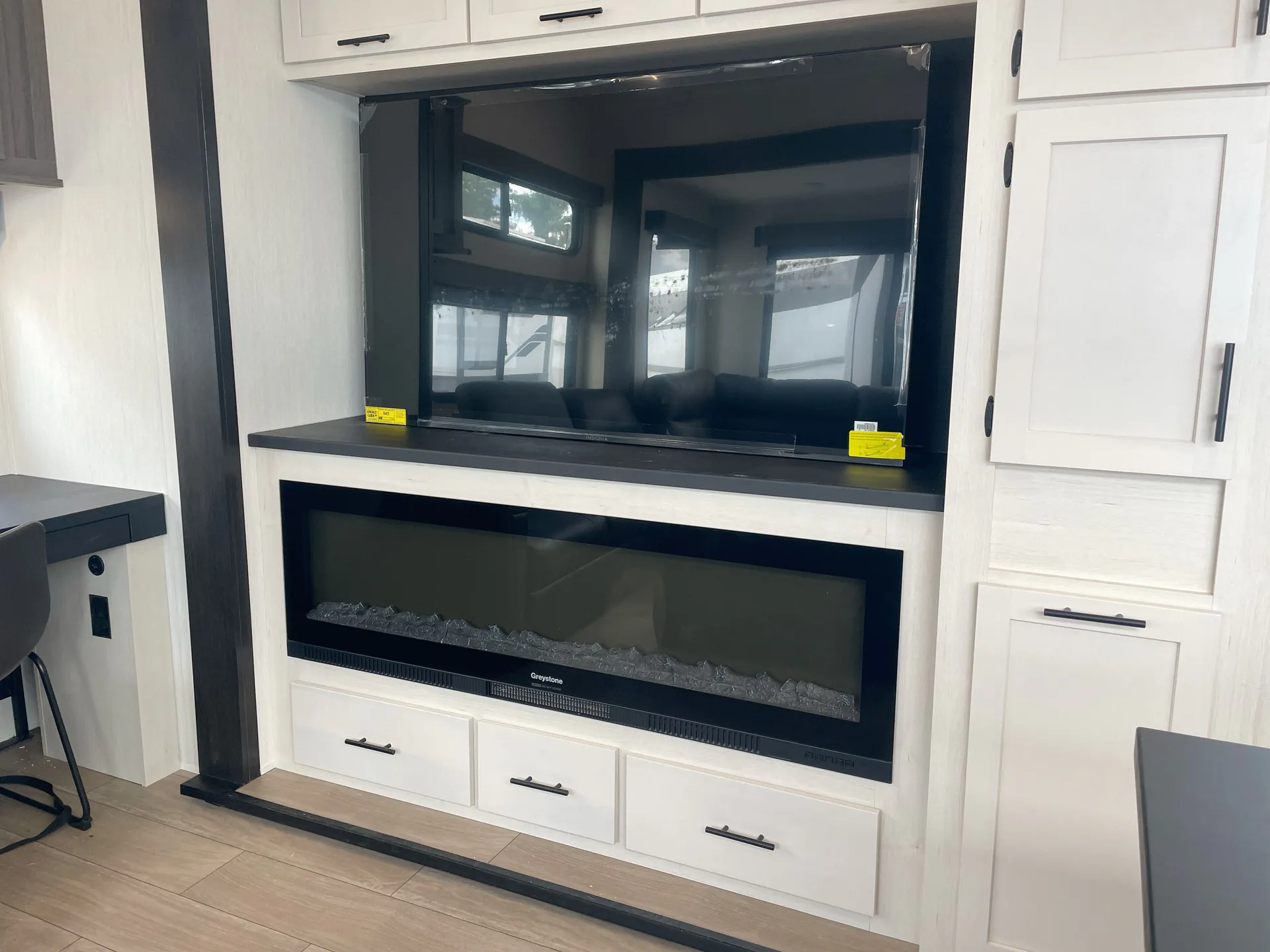 2026 Forest River Arctic Wolf 38LEAH.G — Living area entertainment wall with electric fireplace, television, drawers, and surrounding cabinetry