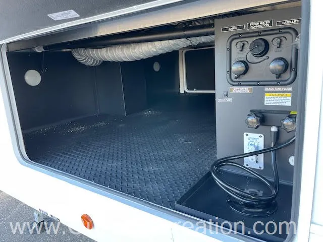 2026 Forest River Arctic Wolf 38LEAH.G — An exterior cargo/service compartment containing labeled fresh-water, cable, satellite, and waste-tank connections