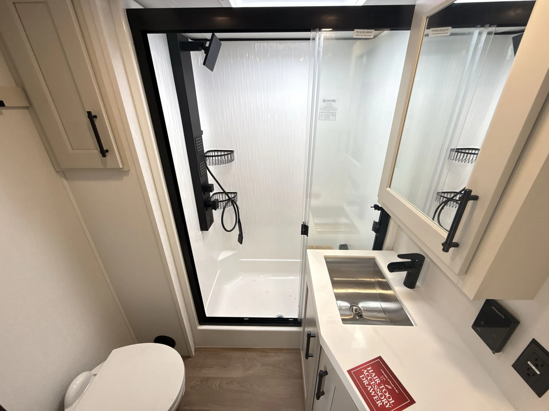 2026 Grand Design Solitude 391DL — Fifth wheel bathroom with glass shower, toilet, mirrored vanity, rectangular sink, and black fixtures