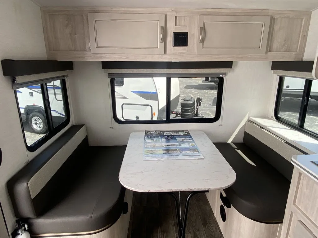 2026 Gulf Stream Vista Cruiser 19ERD — Travel trailer dinette with opposing upholstered benches, table, windows, and overhead storage