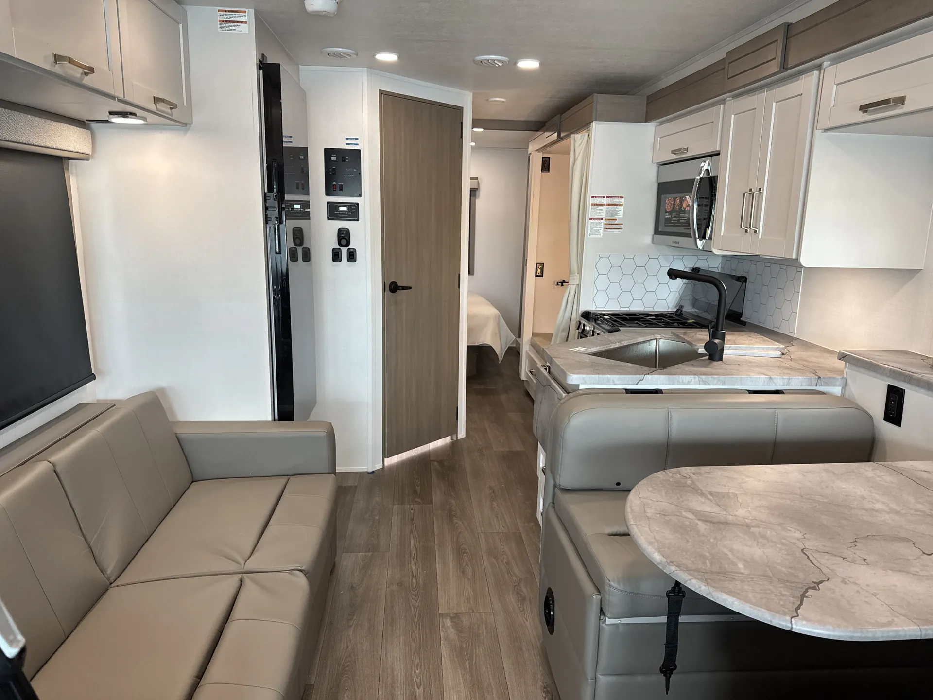2027 Jayco Alante 29F — Class A motorhome kitchen with sink, range, microwave, and cabinetry facing a sofa and dinette along the central aisle
