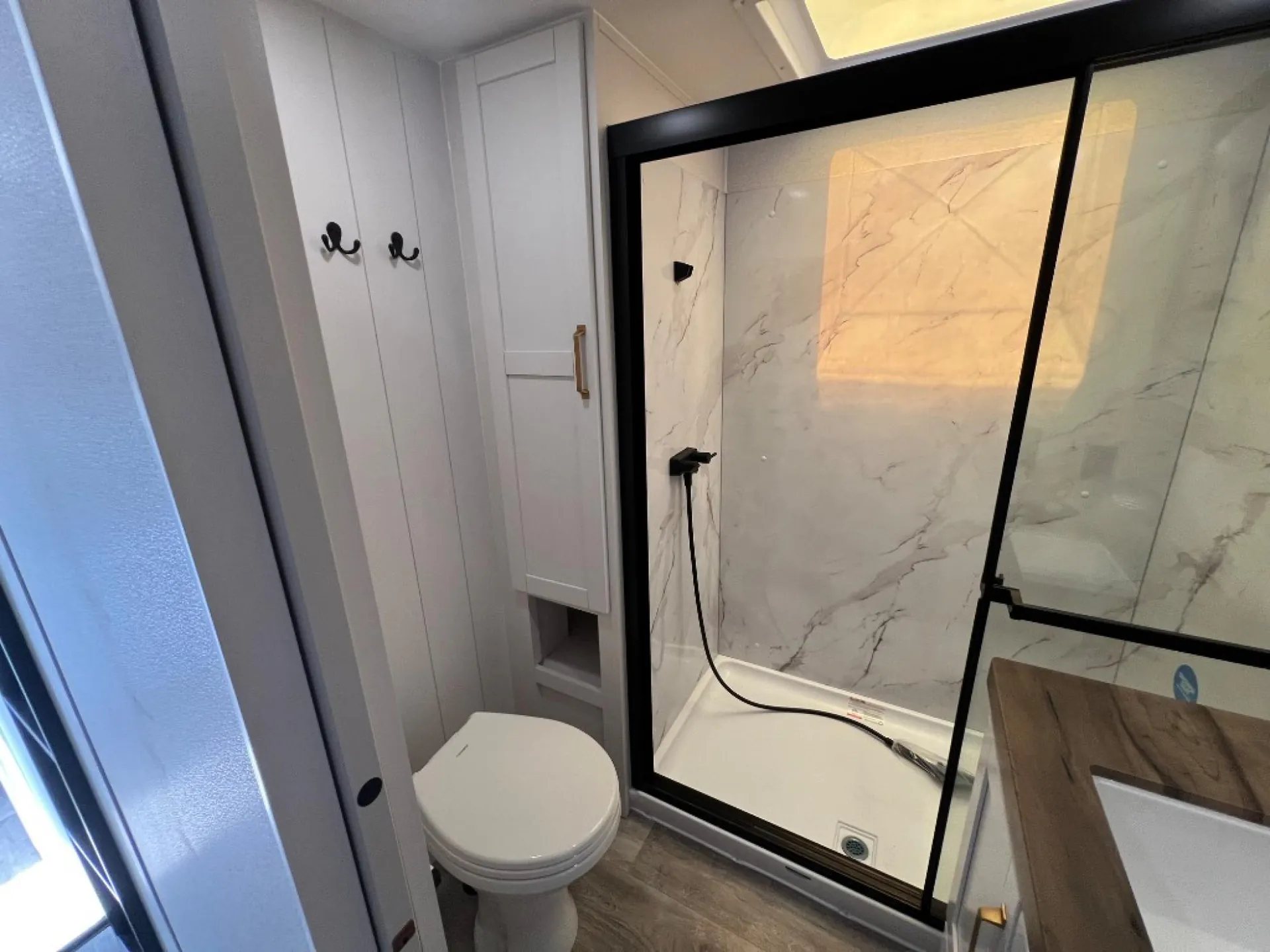 2027 Jayco Eagle 355MBQS — RV bathroom showing toilet, glass shower enclosure, wall storage, and vanity edge