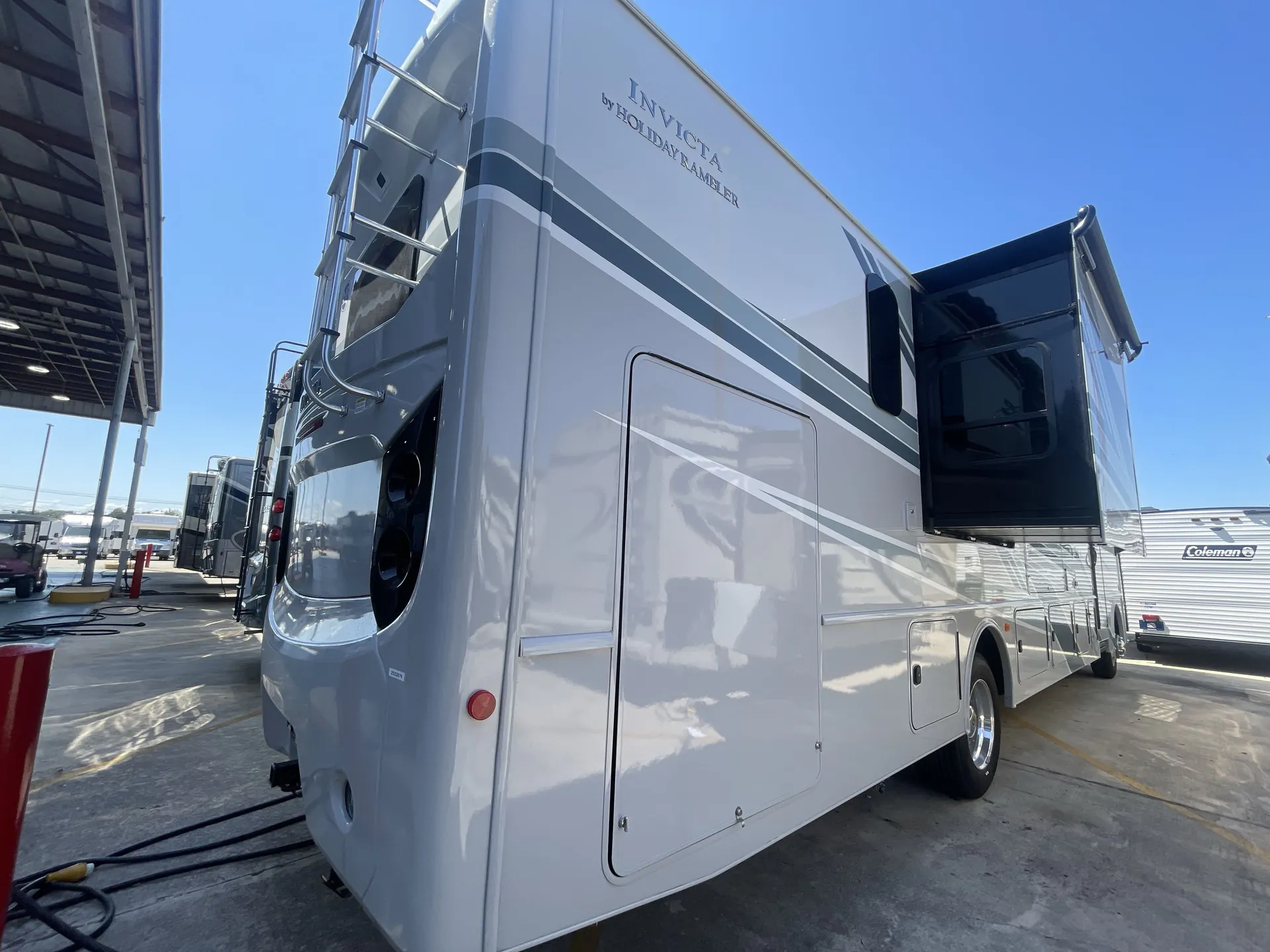 2026 Holiday Rambler Invicta 36Y — Wide photograph visibly shows the outside rear and side of the Invicta motorhome, including body, slide-out, ladder, and exterior compartments
