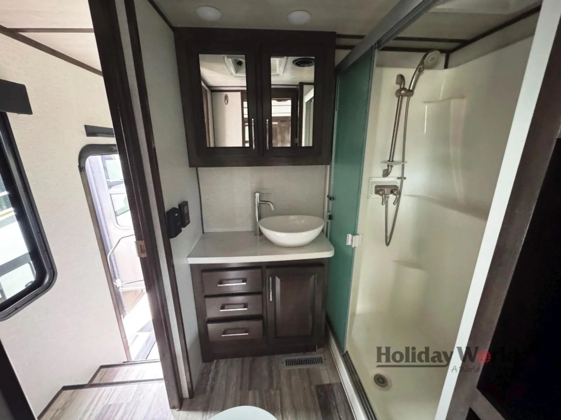 2022 Dutchmen Voltage 4225 — Fifth-wheel bathroom showing vessel sink, mirrored storage cabinet, and enclosed shower