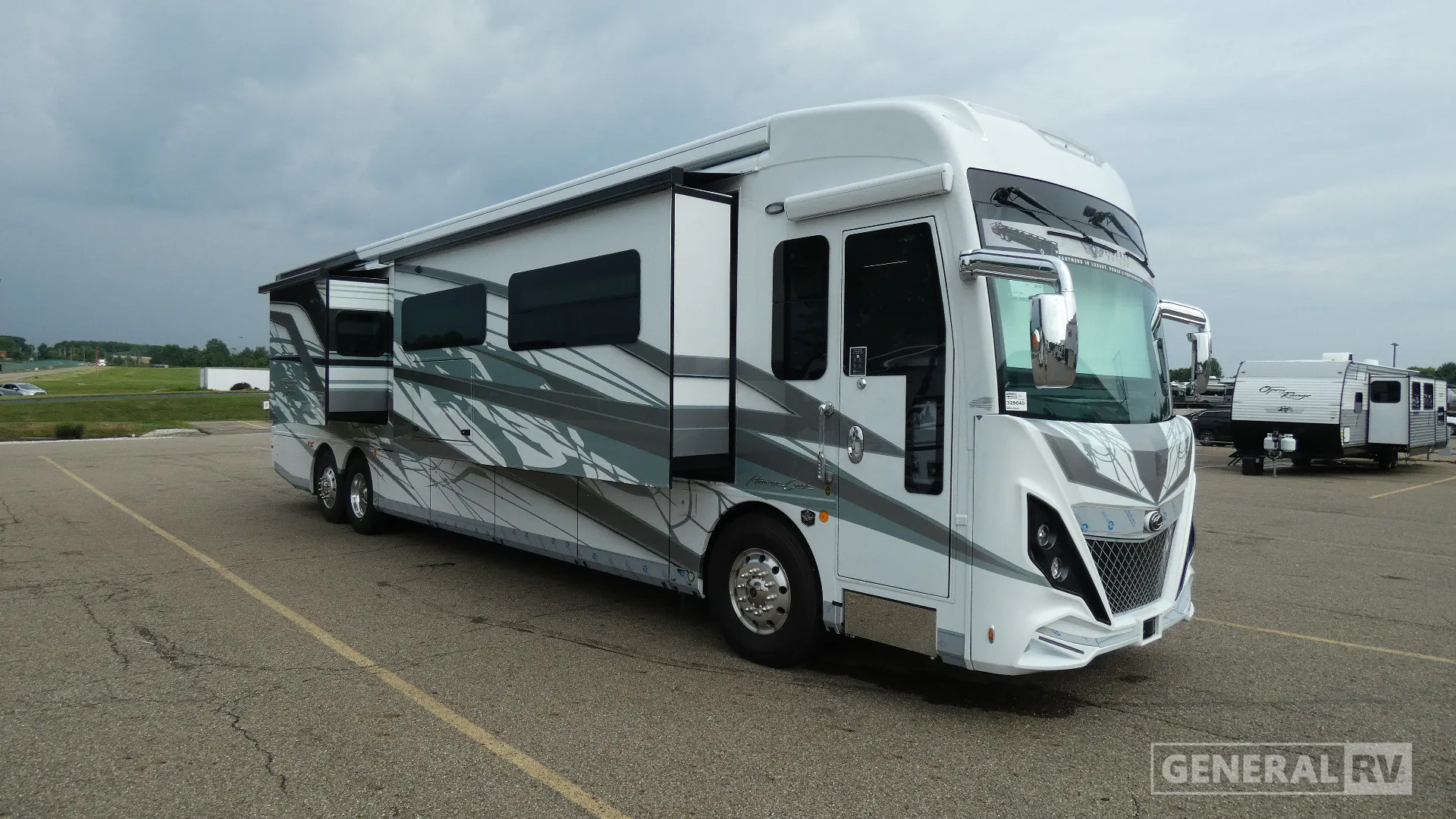 2026 American Coach American Dream 45A — The front and side exterior of a motorhome parked outdoors, with awning and slide-outs
