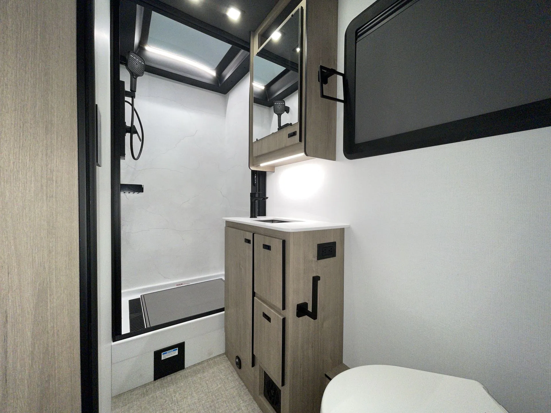 2027 Grand Design Lineage Series F 31ZW — Motorhome bathroom with shower, vanity sink, mirrored cabinet, and partial toilet