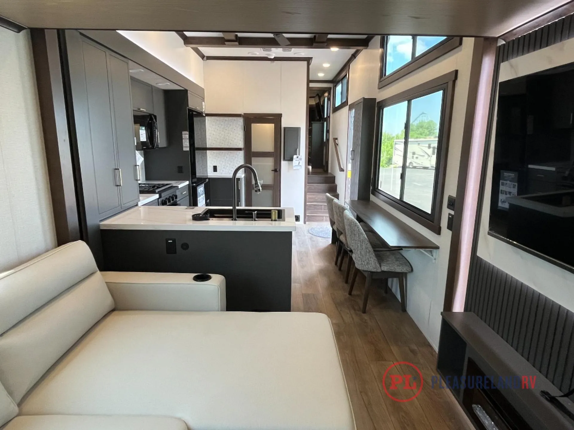 2025 Forest River Cedar Creek Cottage 41FWC — Kitchen island and appliances face a lounge sofa and window-side dining counter along the fifth wheel interior