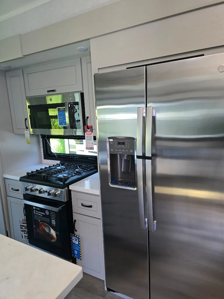 2026 Jayco North Point 377RLBH — Kitchen with stainless refrigerator, microwave, gas range, oven, drawers, and countertop