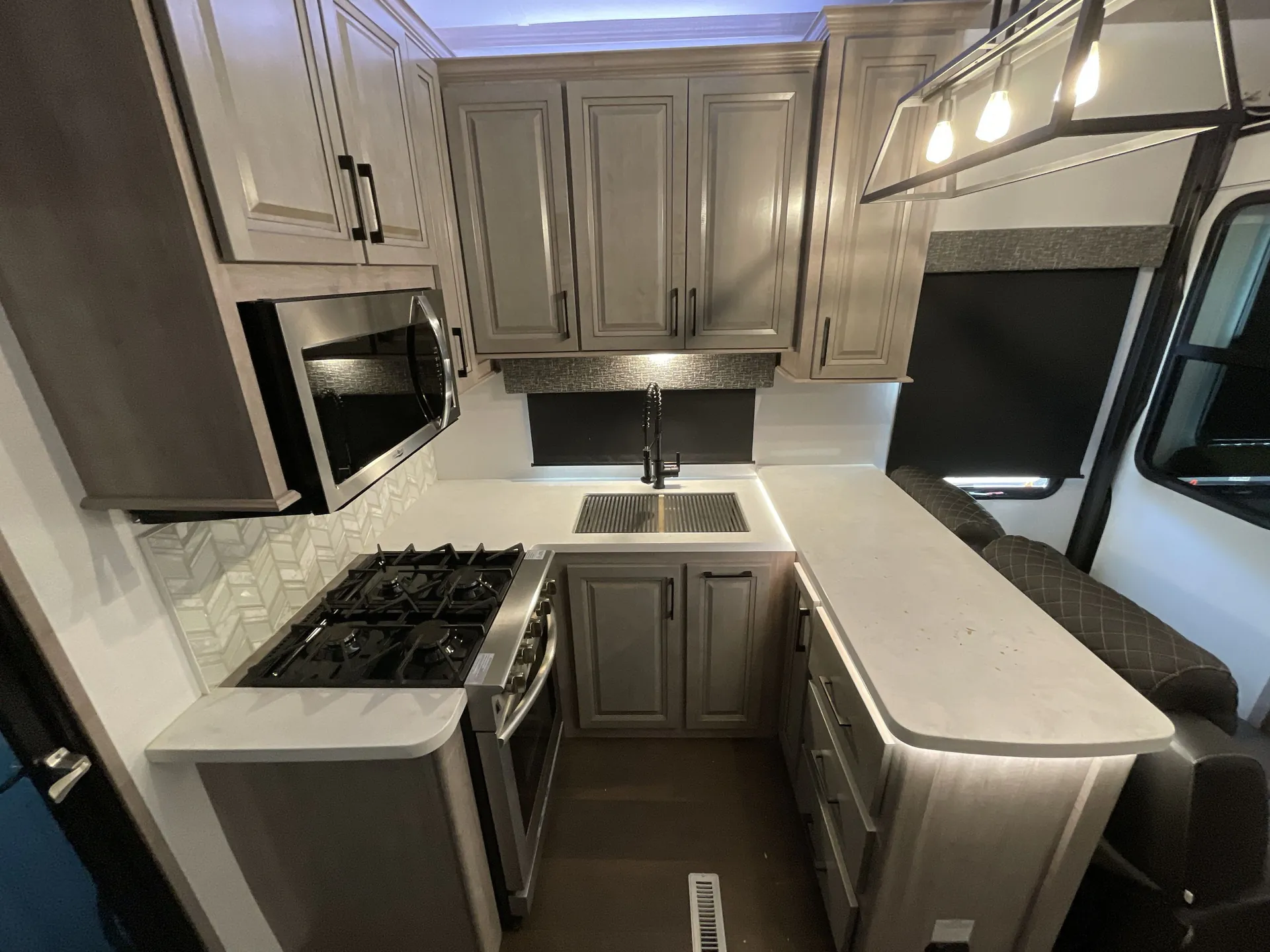 2023 Dutchmen Voltage 4225 — Fifth wheel kitchen with island counter, sink, gas range, microwave, cabinetry, and adjacent seating