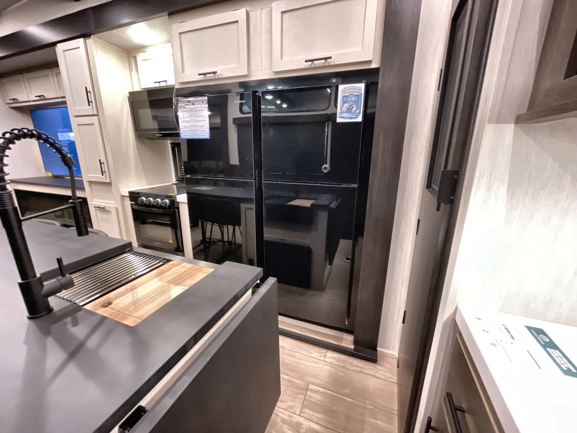 2026 Forest River Arctic Wolf 38LEAH.G — Fifth-wheel kitchen island with sink, cutting board, range, microwave, refrigerator, and surrounding cabinets