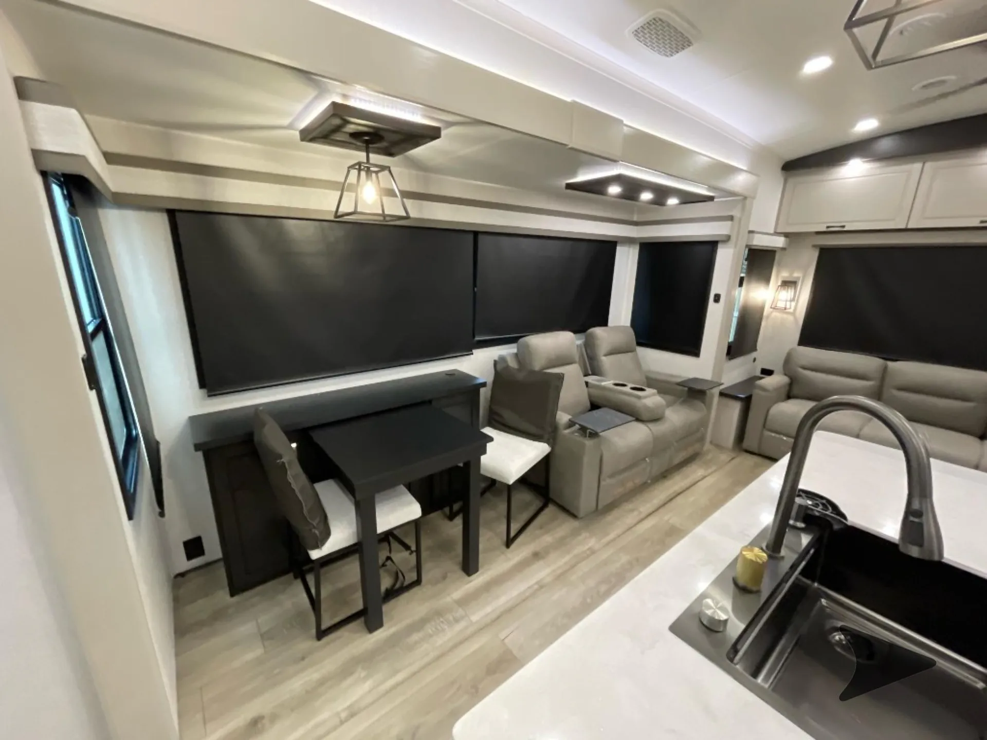 2026 Jayco North Point 377RLBH — Fifth-wheel interior overview with living recliners and sofa, dining table, and kitchen island sink and faucet