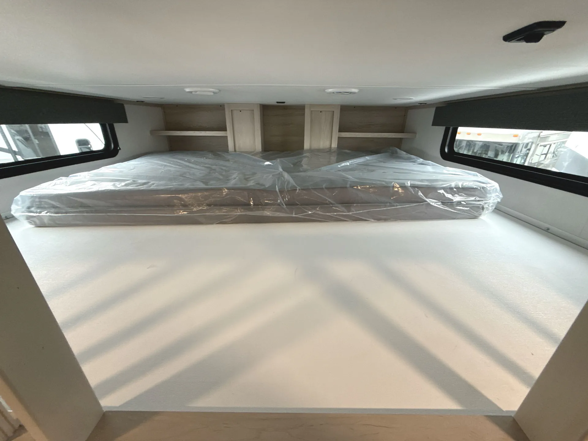 2026 Grand Design Solitude 391DL — Over-cab sleeping platform with a mattress, side windows, and open storage shelves