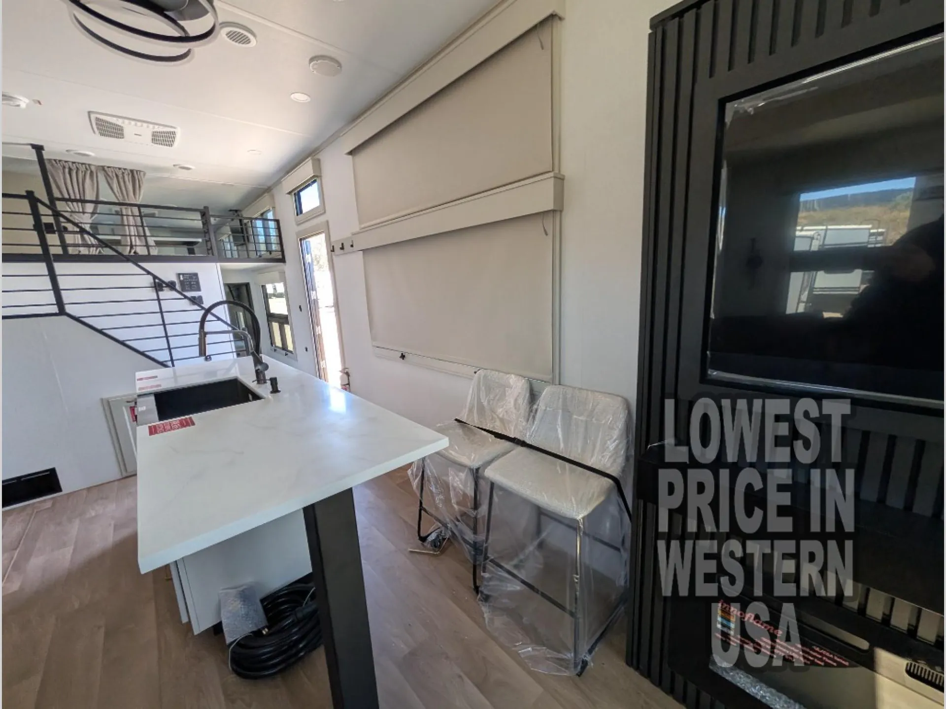 2026 Grand Design Foundation 42GD — Destination trailer dining counter with two chairs beside the kitchen island and staircase leading to an overhead loft