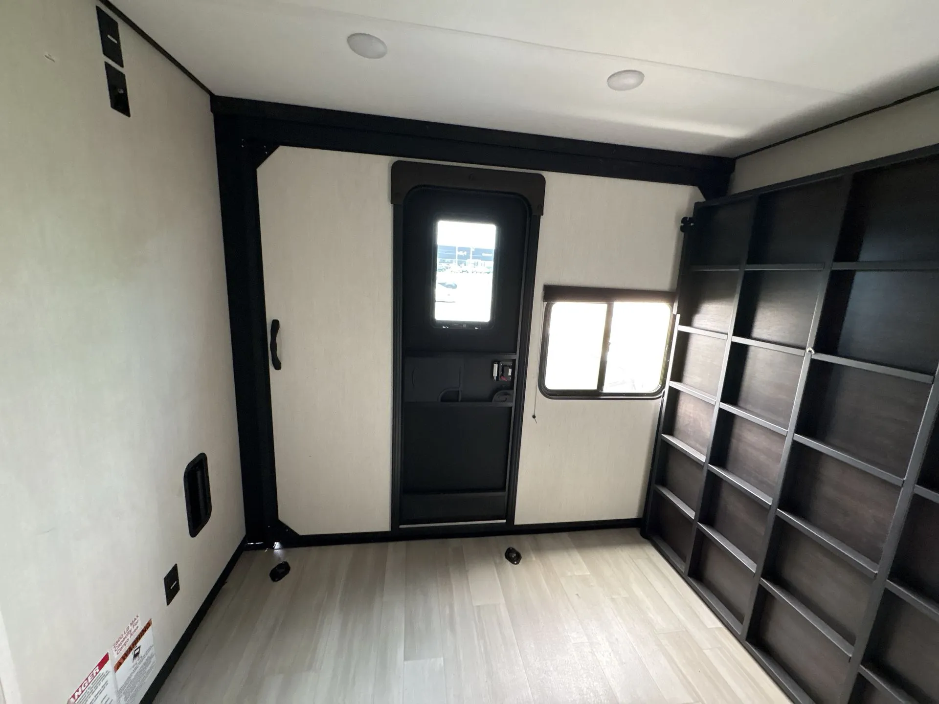 2026 Forest River Cherokee Wolf Pack 397STAY — Empty travel trailer garage with broad floor, tie-down points, large wall shelving, rear entry door, and window