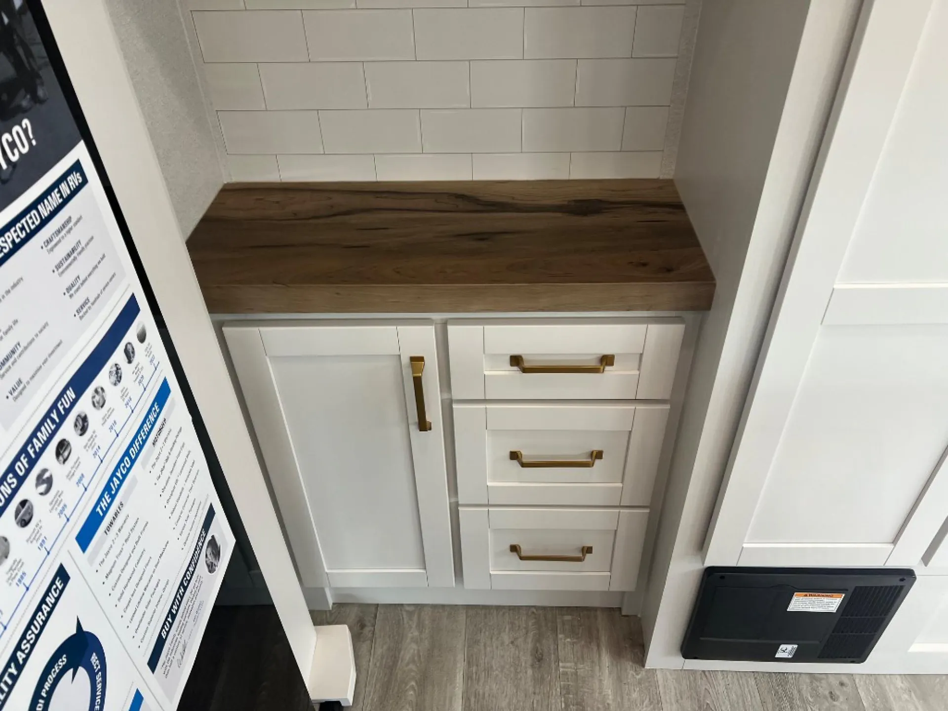 2027 Jayco Eagle 355MBQS — Kitchen cabinet base with wood countertop, tile backsplash, drawers, and a vent panel