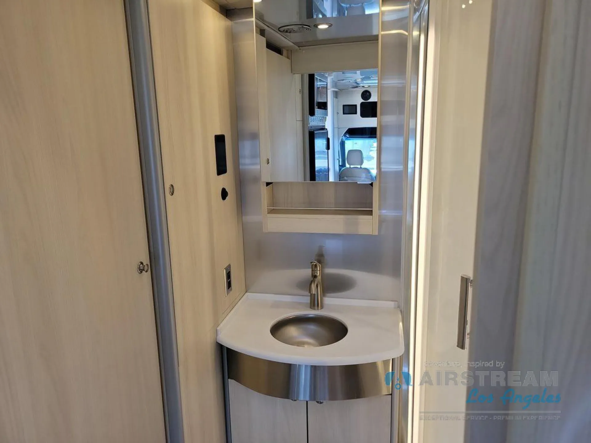 2026 Airstream Atlas Murphy Suite — Class B van bathroom vanity with round sink, faucet, mirrored cabinet, and surrounding cabinetry