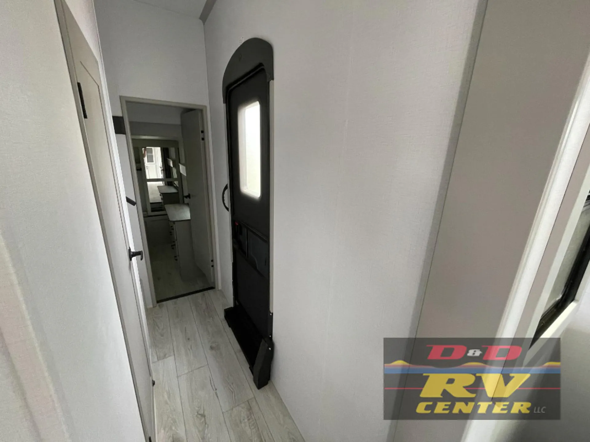 2026 Keystone Montana High Country 377FL — Fifth wheel entry corridor with an open exterior door, interior doorway, and light wood-look flooring