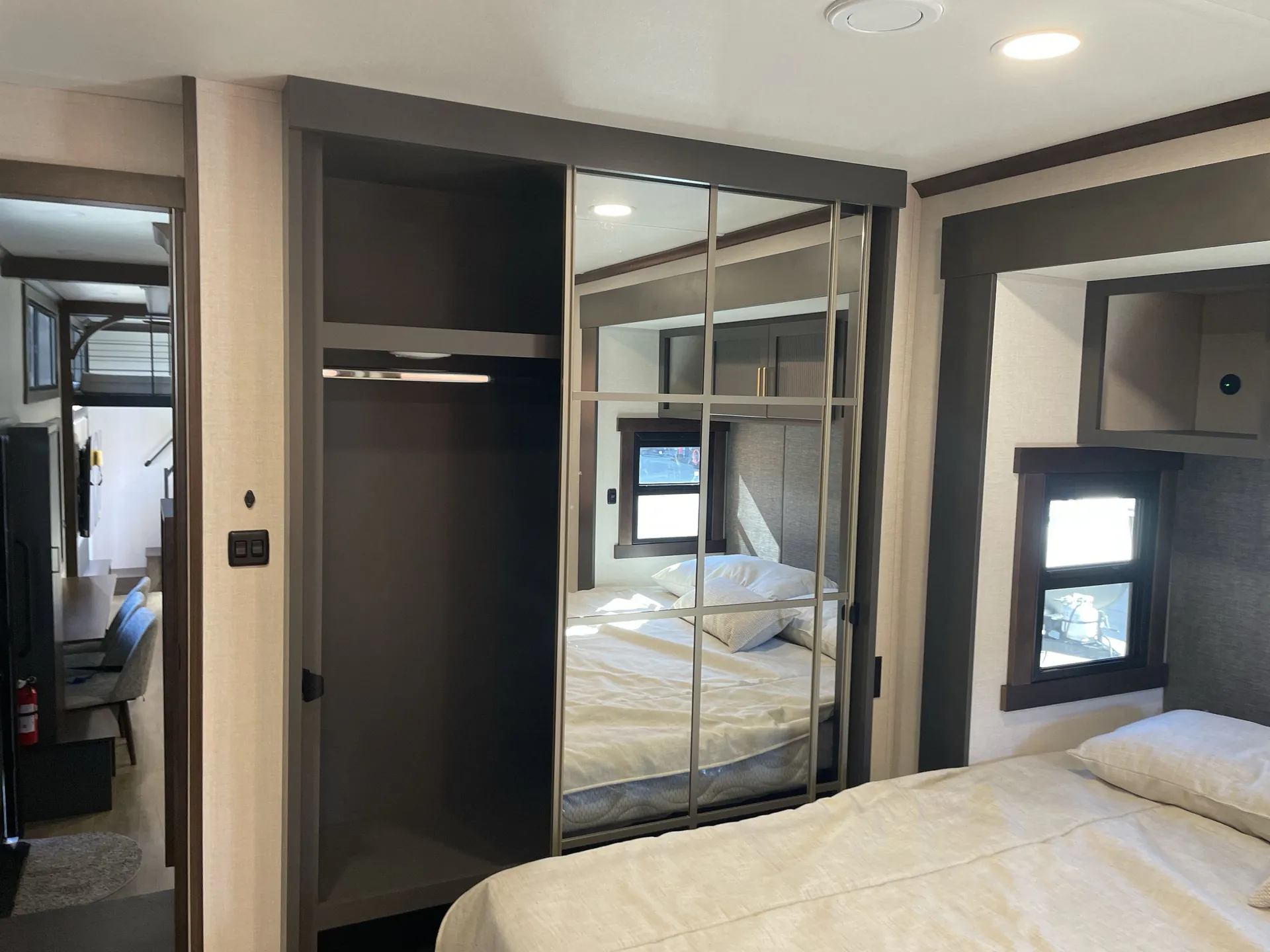 2026 Forest River Cedar Creek Cottage 41FWC — Main bedroom with bed, mirrored wardrobe doors, open closet, and doorway toward the adjoining living area
