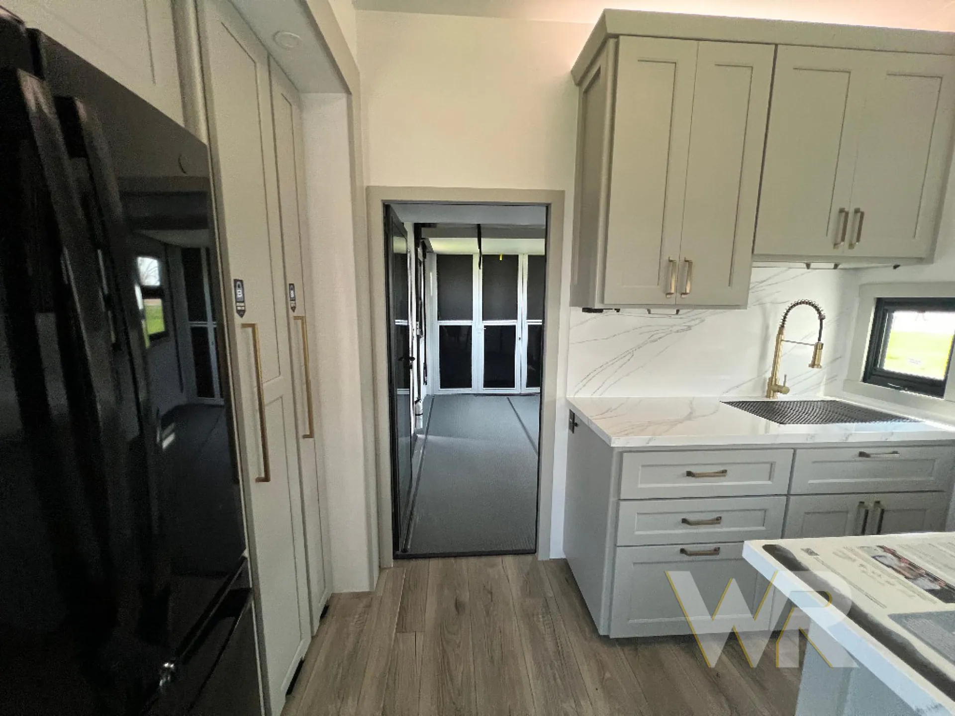 2026 Brinkley Model G 3950 — Fifth wheel kitchen with refrigerator, sink, countertop, cabinets, and a direct view into the garage