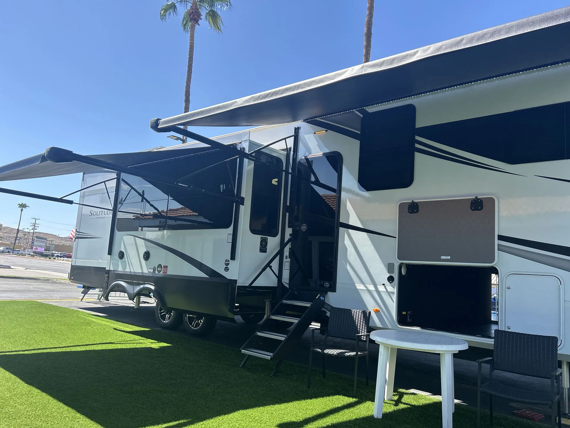 2026 Grand Design Solitude 391DL — Wide exterior photograph of the fifth-wheel RV with slide-outs, awnings, entry steps, and storage doors