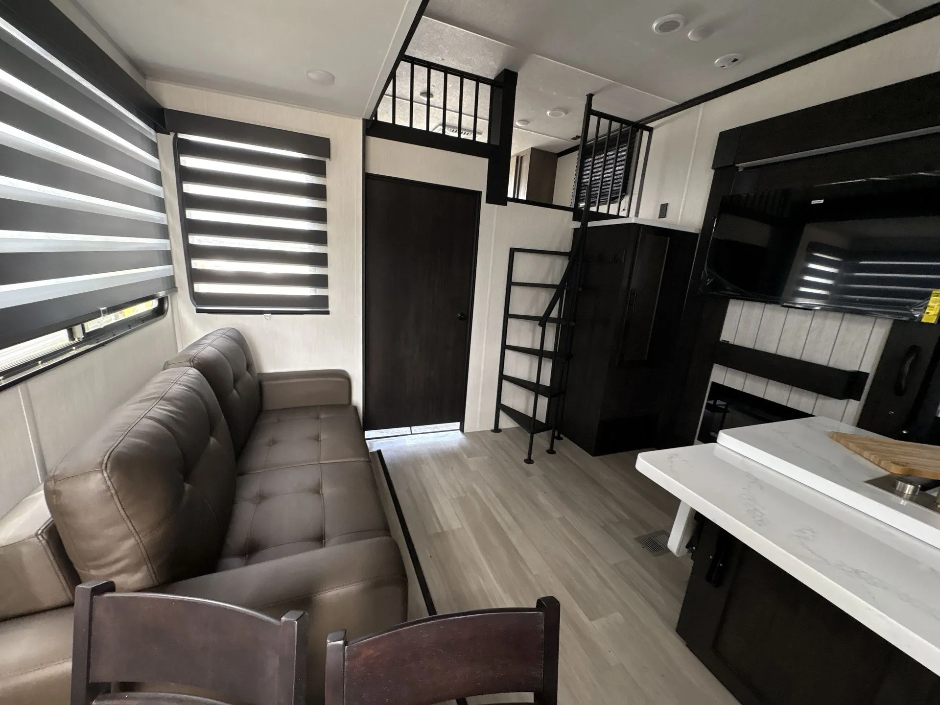 2026 Forest River Cherokee Wolf Pack 397STAY — Travel trailer overview with sofa, dinette chairs, kitchen counter and sink, television, and loft stairs