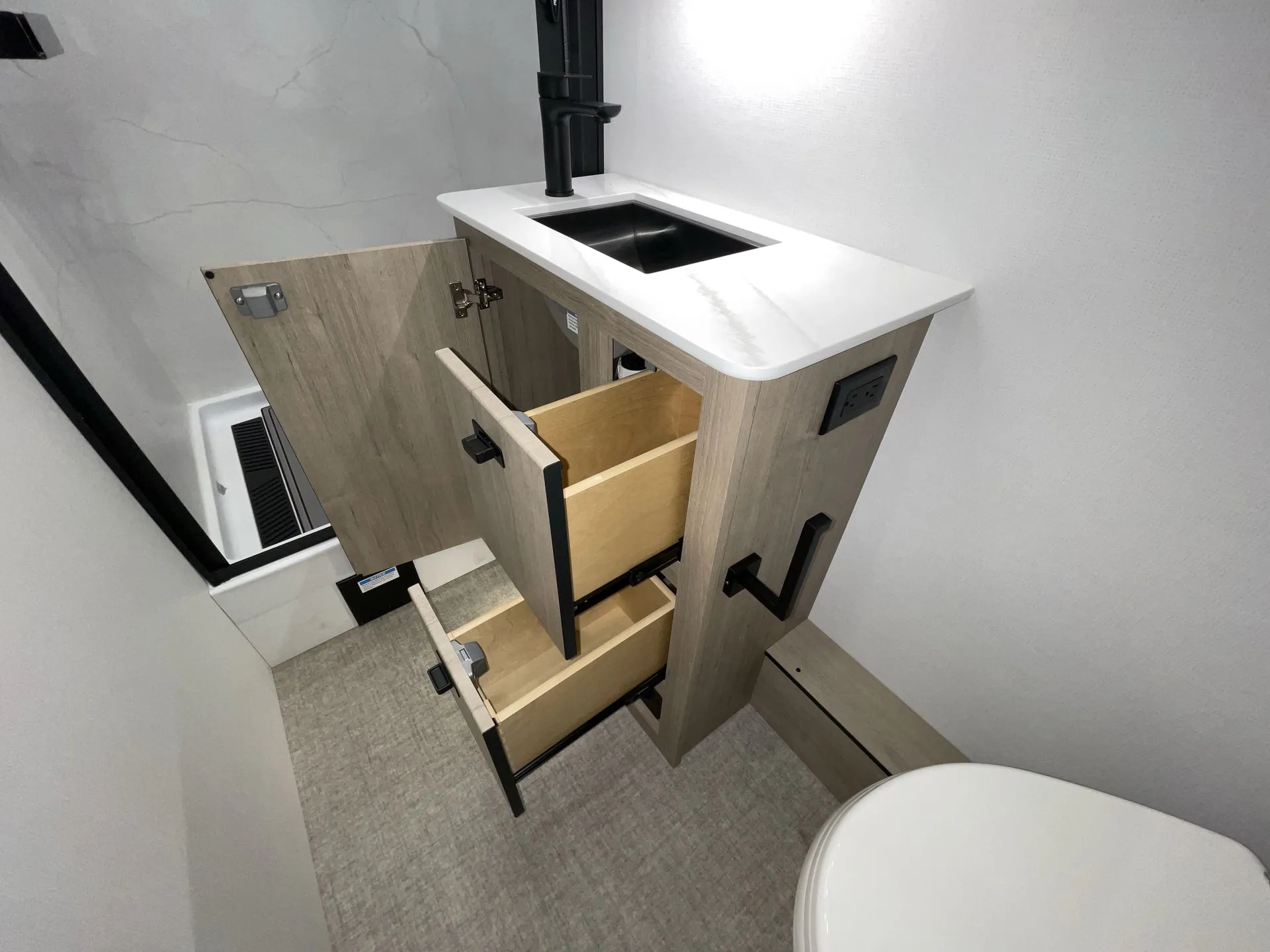 2027 Grand Design Lineage Series F 31ZW — Bathroom vanity with sink, open drawers, cabinet storage, and partial toilet