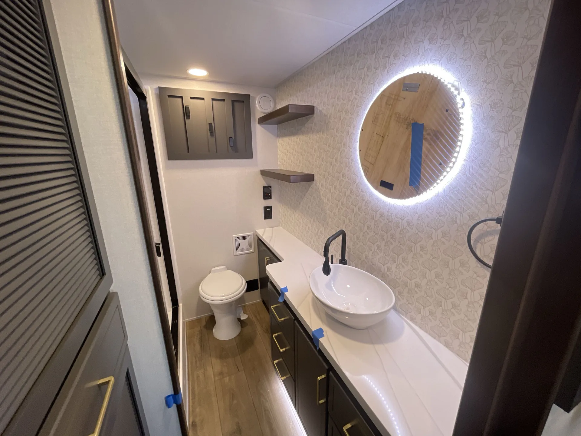 2026 Forest River Cedar Creek Cottage 41FWC — Bathroom vanity with vessel sink, illuminated round mirror, toilet, cabinets, and shelves