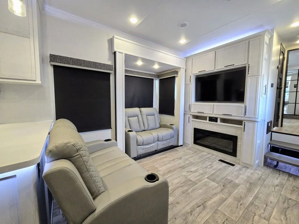 2025 Dutchmen Voltage 4225 — Fifth wheel living room with opposing recliners, large windows, entertainment center, and electric fireplace